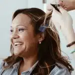 person cutting hair of woman in blue denim jacket