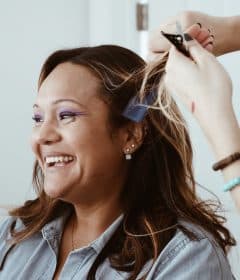 person cutting hair of woman in blue denim jacket